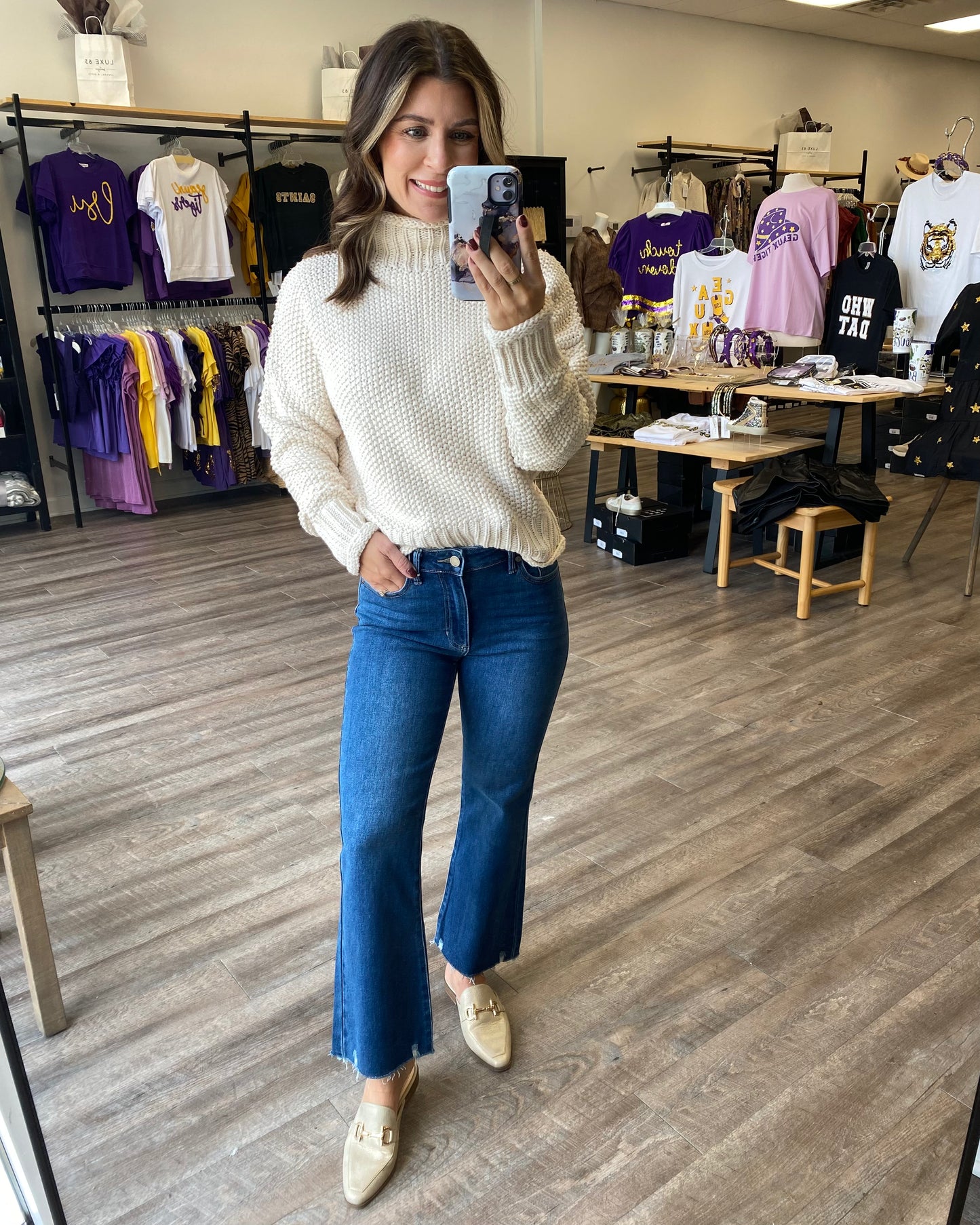 An ivory knit sweater tucked into blue jeans.