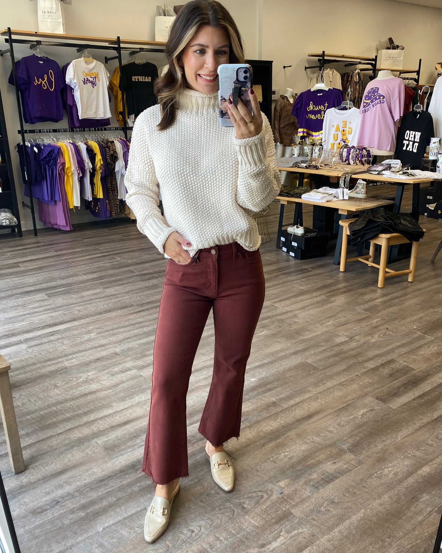 An ivory knit sweater tucked into rust colored jeans.