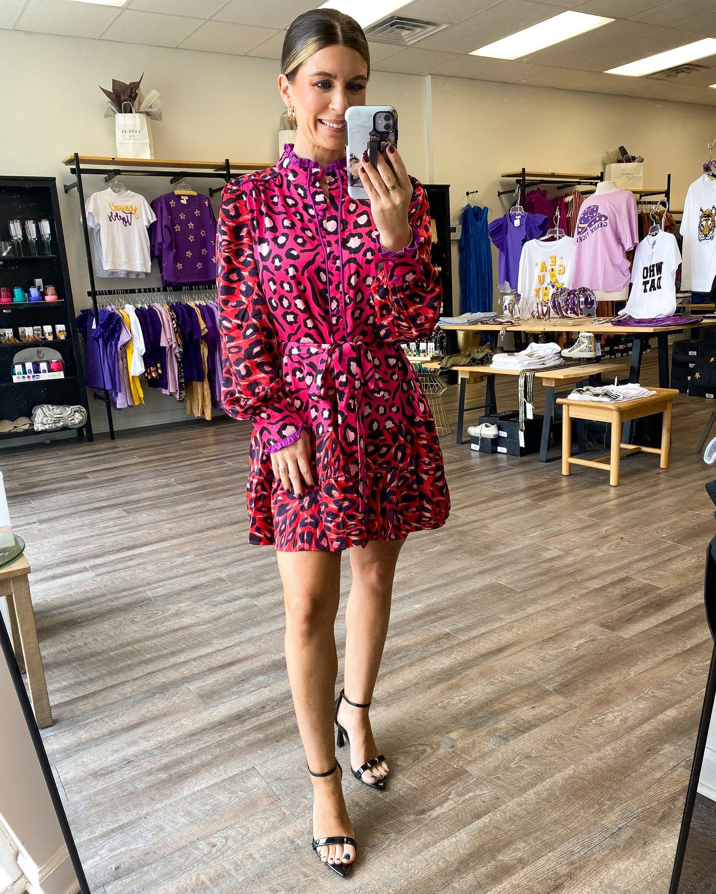 A pink and red dress with all over leopard print, button front, and tie waist