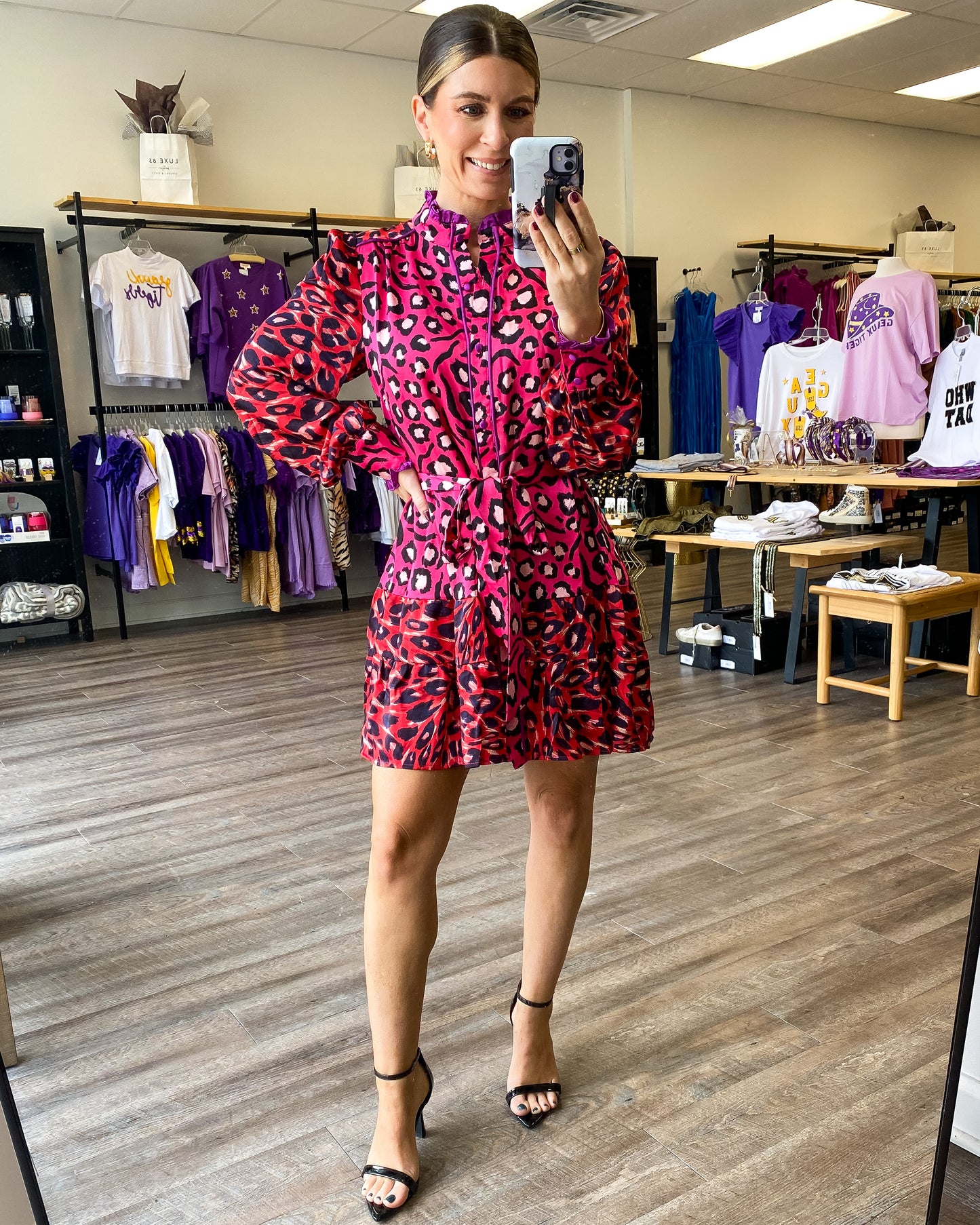 A pink and red dress with all over leopard print, button front, and tie waist.