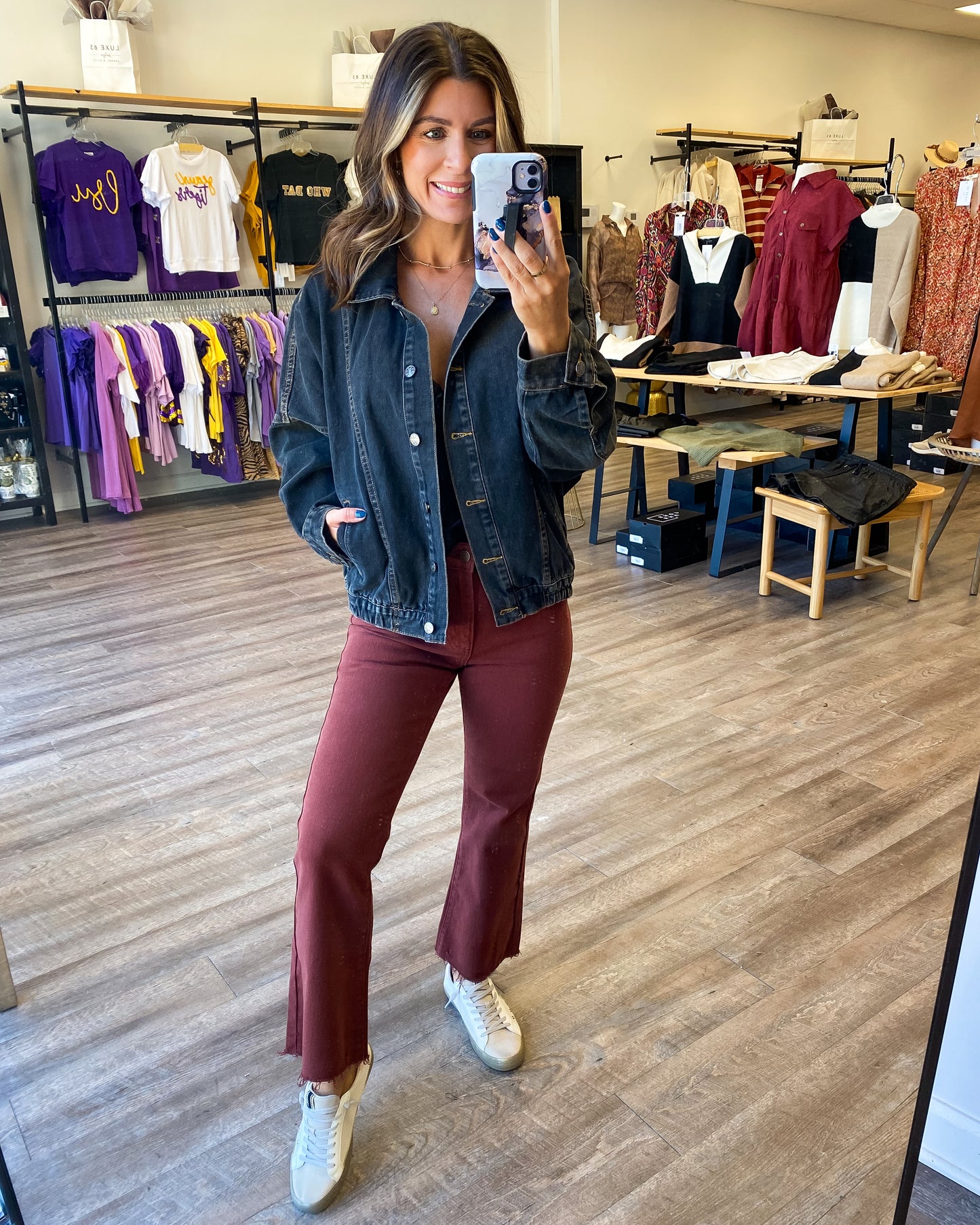 Model is photographed wearing a washed black denim jacket paired with rust jeans.