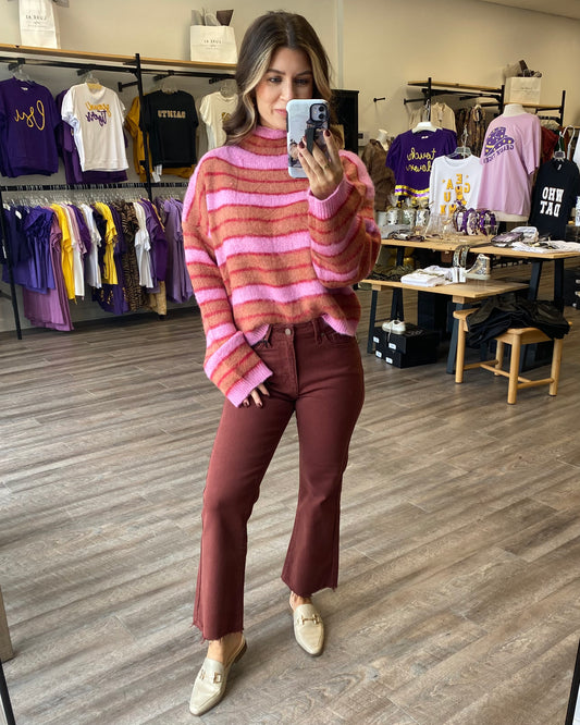 A fuzzy, soft pink sweater with rust and darker pink stripes