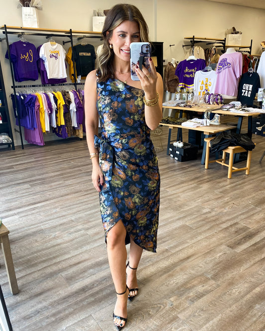 A gorgeous one shoulder dress with an overlapping tie waist.  The dress has a beautiful floral print all over and a tie at the waist with a tulip hem.